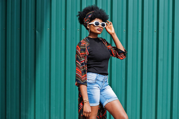 African woman with afro hair, in jeans shorts and white sunglass - Photo, image