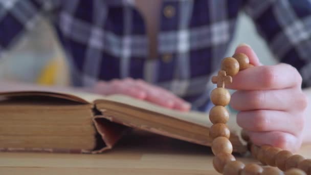 Gros plan d'un chapelet entre les mains d'une femme lisant la Bible
 - Séquence, vidéo