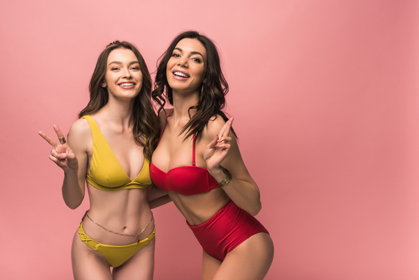 deux jolies filles en bikini montrant des signes de paix isolés sur rose
 - Photo, image