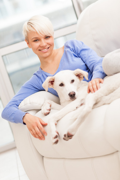 Woman sitting with young dog on the sofa - Фото, зображення