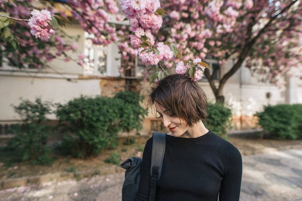 beautiful smiling girl near a flowering sakura tree - Foto, afbeelding