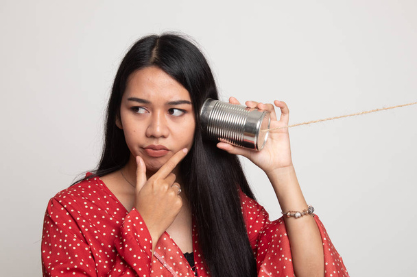 Young Asian woman hearing with tin can phone and thinking. - Foto, Bild