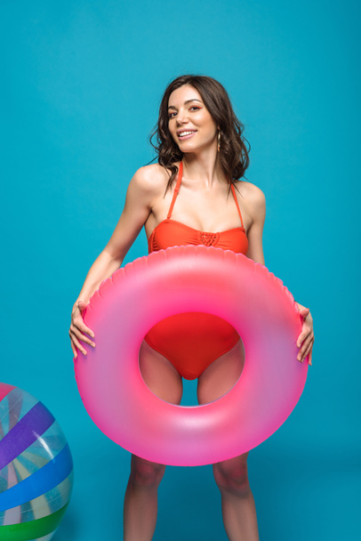 pretty girl in swimsuit holding inflatable swim ring on blue - Zdjęcie, obraz