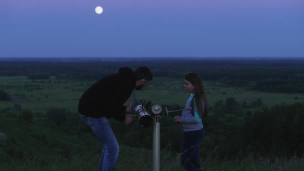 Father and his daughter look through a telescope at the moon - Footage, Video