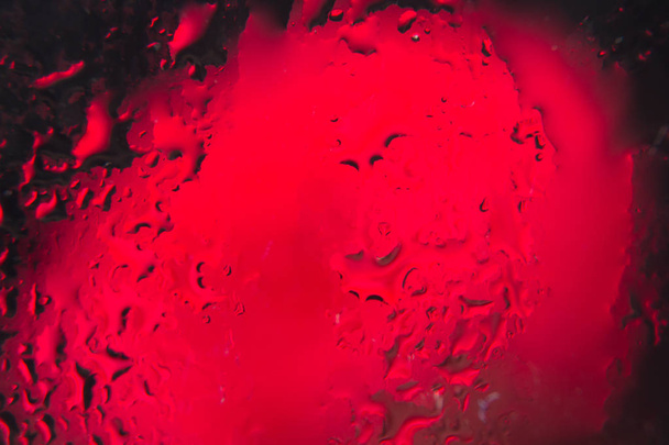 bonita flor roja con sus pétalos llenos de gotas de agua, detrás de un vaso lleno de gotas de agua
. - Foto, Imagen