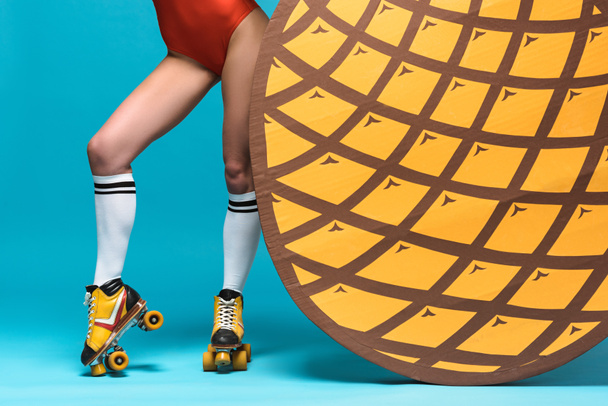 cropped view of woman in knee socks and roller skates near decorative pineapple on blue - Photo, Image