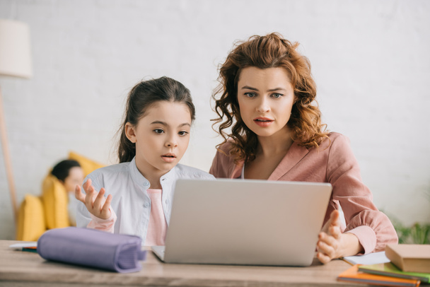 discouraged woman and daughter gesturing while using laptop together - Photo, Image