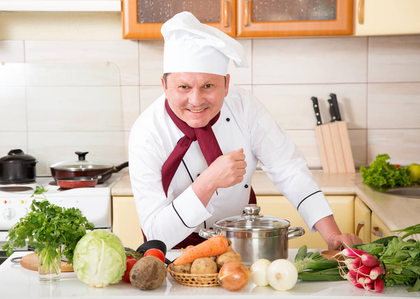 Portrait of a male cook in the kitchen. Male chef cooks food. - Фото, изображение