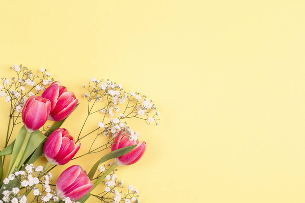 Strauß von Tulpen und Zigeunerblumen auf gelbem Grund. Platz für Text. flache Lage, Draufsicht. - Foto, Bild