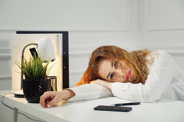 Набридла жінка-працівник лежить за офісним столом Подумайте про вирішення проблеми
 - Фото, зображення