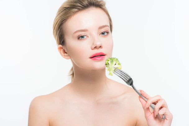 attractive naked woman holding silver fork with broccoli near pink lips isolated on white   - Valokuva, kuva