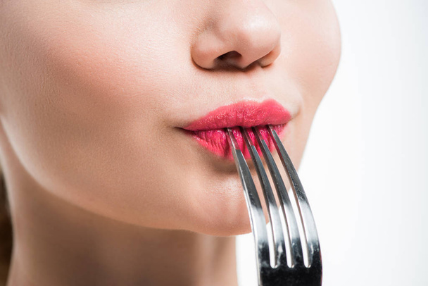 vista ritagliata della donna che tiene la forchetta d'argento vicino alle labbra rosa isolate sul bianco
   - Foto, immagini