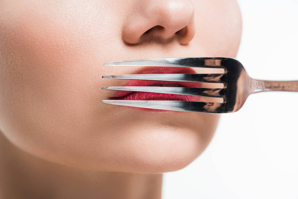 vista recortada de la mujer sosteniendo tenedor de plata cerca de los labios aislados en blanco
  - Foto, Imagen