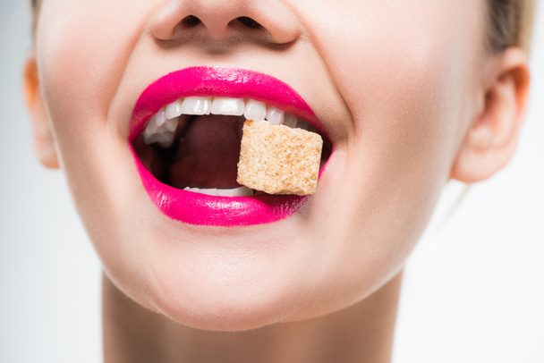 bijgesneden beeld van gelukkige vrouw die suiker kubus eet op wit  - Foto, afbeelding