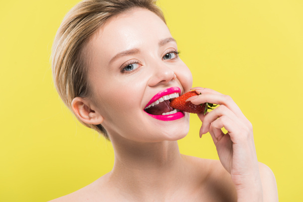 attractive woman with pink lips eating strawberry isolated on yellow  - Photo, Image