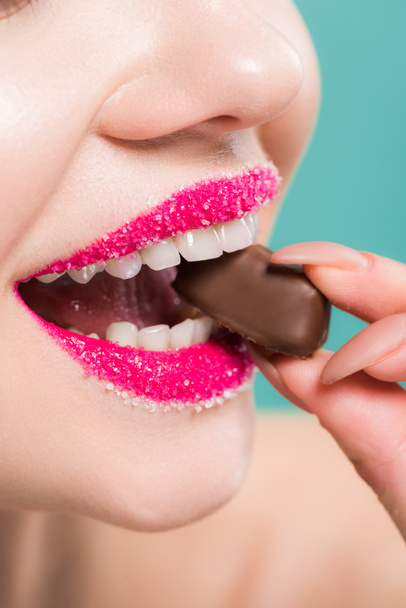 cropped view of happy woman eating chocolate candy isolated on blue   - 写真・画像