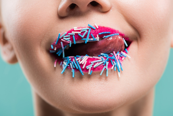 vista ritagliata di giovane donna leccare labbra con spruzzi blu isolati su blu
   - Foto, immagini
