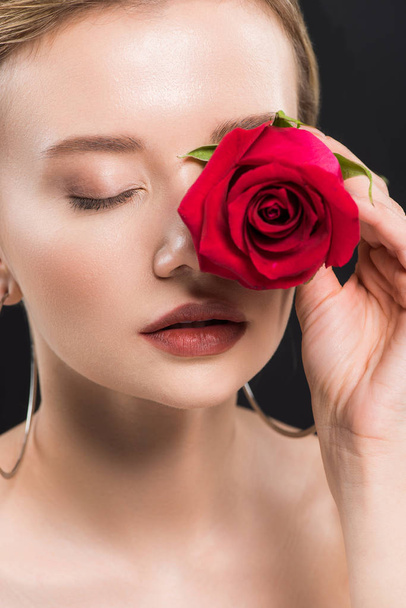 selective focus of young woman holding red rose isolated on black  - 写真・画像