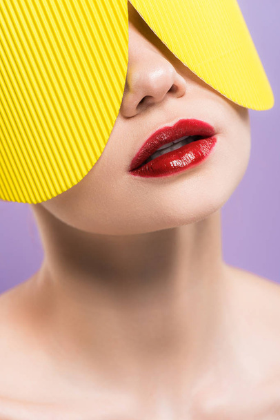 γυμνό κορίτσι με κόκκινα χείλη σε κίτρινο χαρτί γυαλιά απομονώνονται σε μωβ  - Φωτογραφία, εικόνα