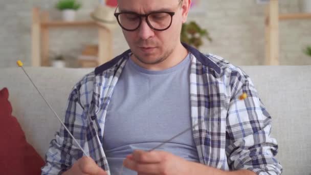 young man with knitting needles in hand knits - Záběry, video