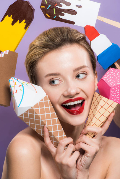 χαρούμενη γυμνή νεαρή γυναίκα που κατέχουν διακοσμητικά κώνους παγωτού απομονώνονται σε μωβ  - Φωτογραφία, εικόνα