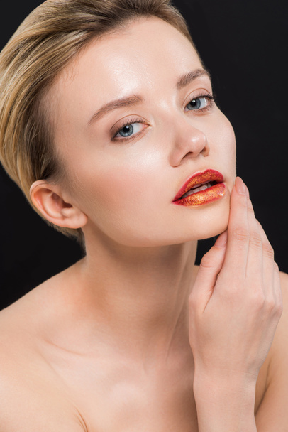 naked and attractive woman with orange lips touching face isolated on black  - Фото, зображення