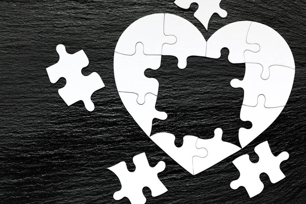 Heart-shaped jigsaw puzzle on color background. Puzzle heart on  - Φωτογραφία, εικόνα