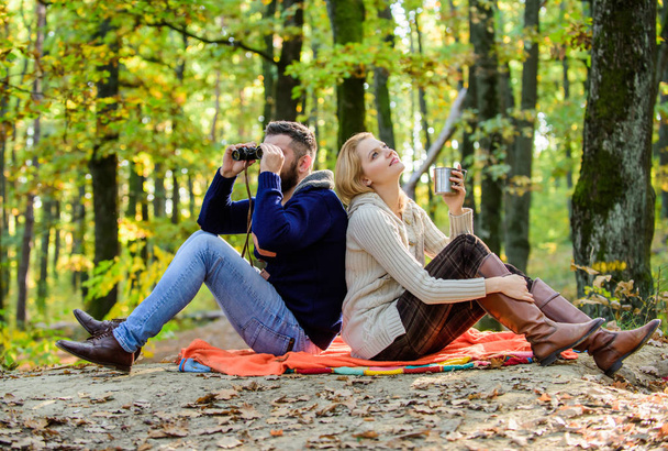 Happy loving couple relaxing in park together. Couple in love tourists relaxing picnic blanket. Man with binoculars and woman with metal mug enjoy nature park. Park date. Relaxing in park together - Photo, Image
