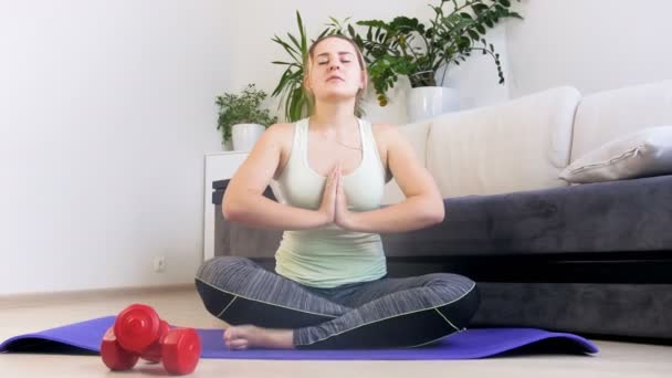 4k záběry krásné mladé ženy meditující na fitness rohoži po provedení fyzického cvičení - Záběry, video