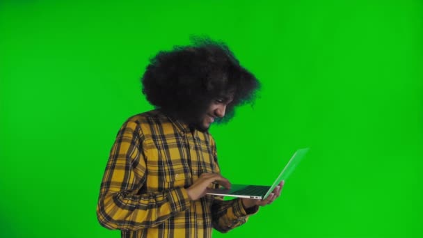 African American man typing at laptop and smiling on green screen or chroma key background. Concept of emotions - Footage, Video