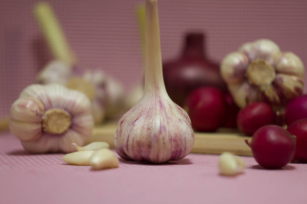 frischer roter Rettich, rote Zwiebeln und Knoblauch. frisches Gemüse auf einem Holzbrett. Gemüse auf rotem Hintergrund. Nützliche, medizinische Produkte. - Foto, Bild