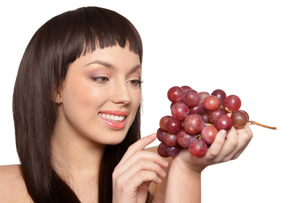 Портрет молодой женщины, позирующей с виноградом на белом фоне
 - Фото, изображение