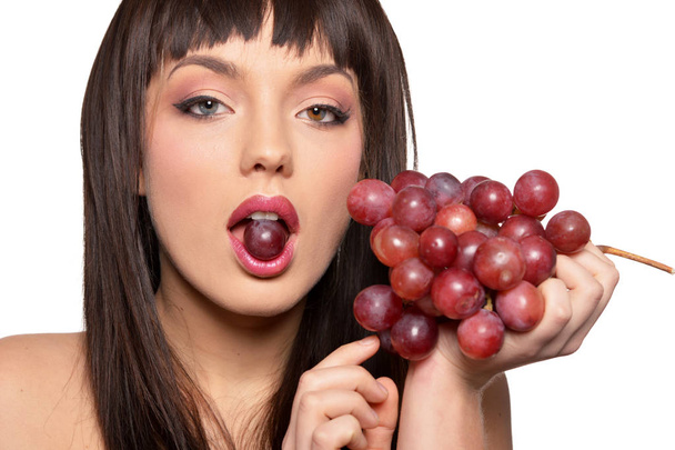 Retrato de una joven posando con uvas aisladas sobre fondo blanco
 - Foto, imagen
