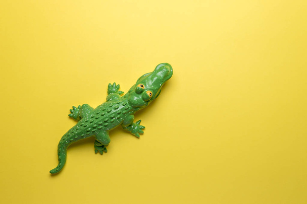 Green crocodile toy on bright yellow background. Minimal art concept. - Photo, Image