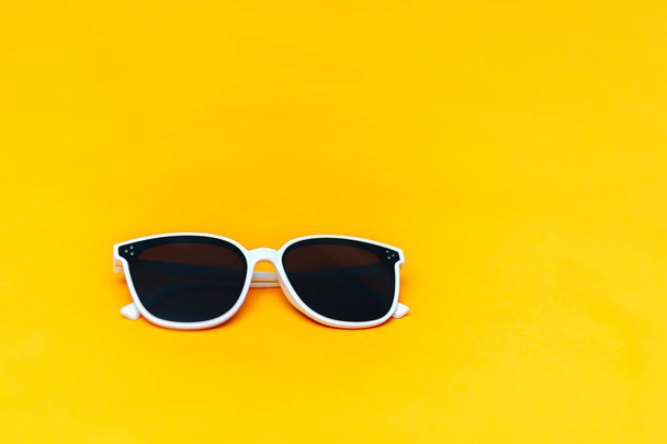 weiße Sonnenbrille auf leuchtend gelbem Hintergrund, Copyspace, der Sommer kommt Konzept - Foto, Bild