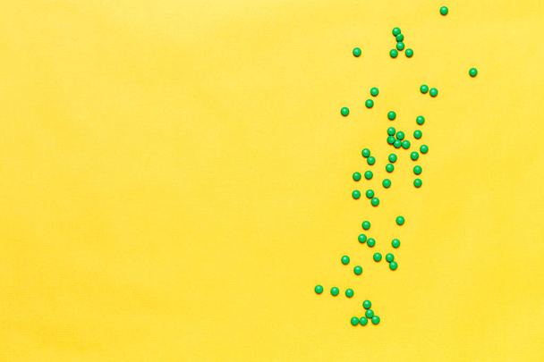 tabletas pequeñas píldoras redondas verdes sobre fondo amarillo. copyspase, espacio para texto
 - Foto, Imagen