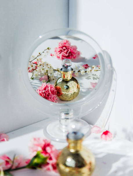 Μπουκάλι άρωμα με καθρέφτη και ανθάρα λουλούδια - Φωτογραφία, εικόνα