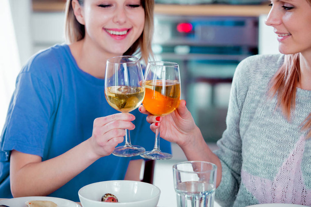 Δύο γυναίκες που πίνουν κρασί στο γυαλί στο σπίτι. - Φωτογραφία, εικόνα