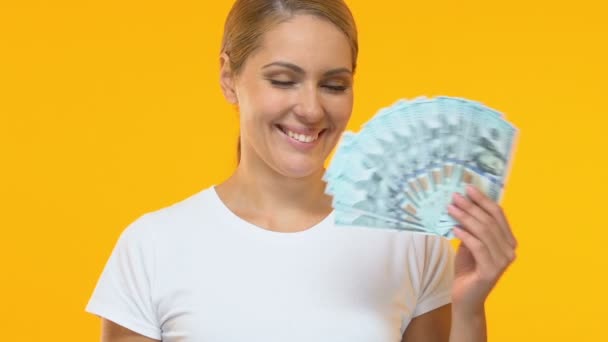 Cheerful woman pointing finger at bunch of dollars, profitable credit terms - Séquence, vidéo
