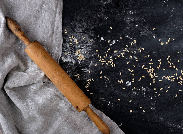  wooden rolling pin on a black background, near a gray linen tow - Valokuva, kuva