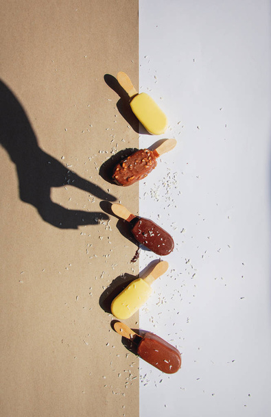 helado en palos con sombra de mano femenina
 - Foto, Imagen