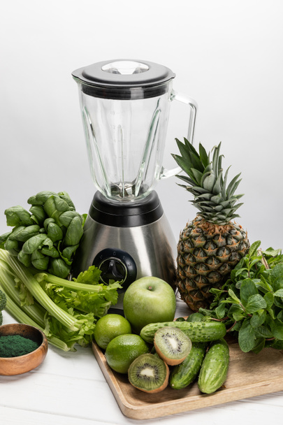 blender near green, fresh vegetables and organic raw fruits on white  - Photo, Image