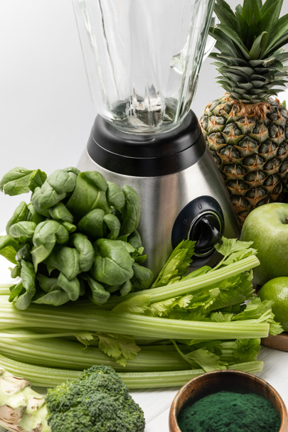 το μπλέντερ κοντά σε φρέσκα φρούτα και βιολογικά πράσινα λαχανικά σε λευκό  - Φωτογραφία, εικόνα