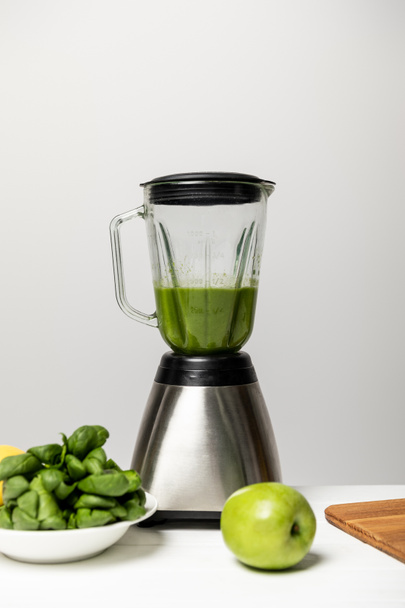 green tasty apple near spinach leaves and blender on grey  - Фото, изображение
