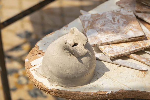 Argila crua para modelagem de cerâmica com uma faca de vidraceiro e ferramentas de moldagem. Verão espaço de trabalho de cerâmica ao ar livre
 - Foto, Imagem