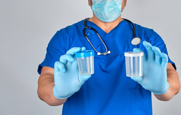 lekarz w niebieskie rękawice jednolite i lateks trzyma pustą plas - Zdjęcie, obraz