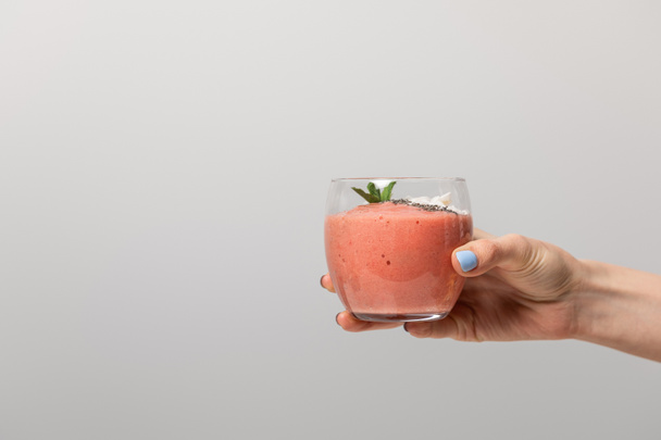 cropped view of woman holding glass with tasty pink smoothie on grey  - Foto, Imagen