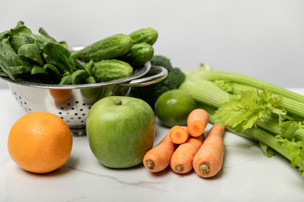 maukkaita ja makeita hedelmiä lähellä kypsiä ja tuoreita vihanneksia harmaalla
  - Valokuva, kuva