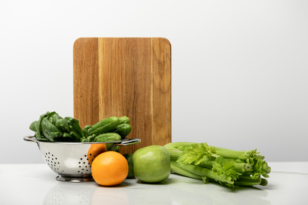 tasty and sweet fruits near ripe, fresh vegetables and wooden cutting board on grey  - Foto, Imagen