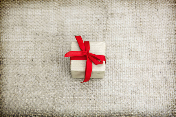 Present and red ribbon isolated on gray cloth background. - 写真・画像